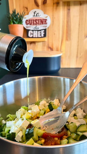 Vinaigrette citronnée au miel versée depuis un shaker NICO® dans une salade estivale avec feta, concombre et maïs, dans une cuisine familiale artisanale.