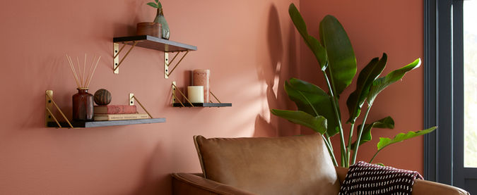 Black floating shelves on a red wall in front of a brown leather chair