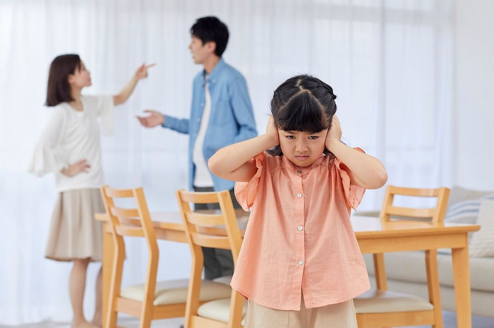 Young girl in distress covering her ears while parents argue in the background, showing the impact of parental conflict and emotional abuse on children.