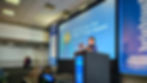 Nati Elimelech taking a photo of the audience while on stage presenting at BrightonSEO in April 2023.
