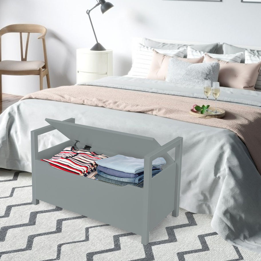 Gray storage bench with open lid and folded clothes
