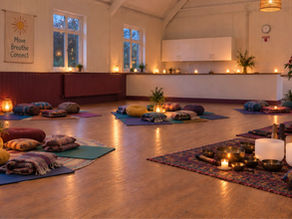 St. Paul's Church Hall setup ready for a sound bath with low lighting, candles, blankets and cushions alongside a large gong