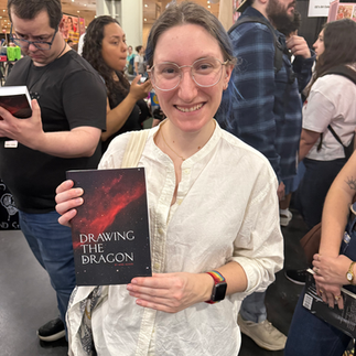 Fans discovering a sci-fi fantasy book series with dragons at a convention booth