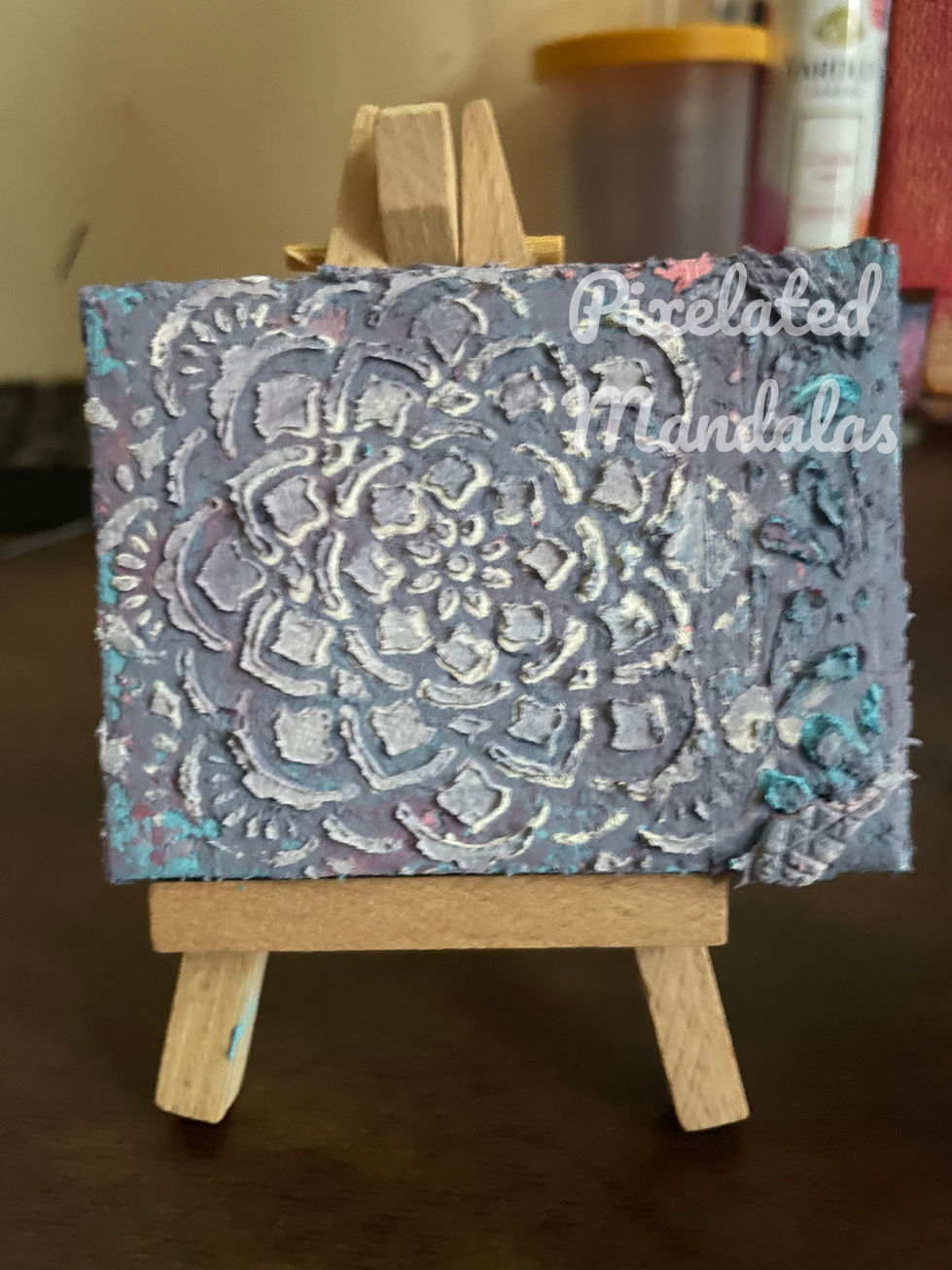 a small painting on an easel that says pixelated mandalas