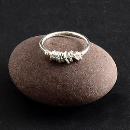 Lightly textured silver rings threaded through a tiny bundle of varying sized hoops, all trapped at the front of the ring by two tiny silver spheres
Perfect to fiddle with!