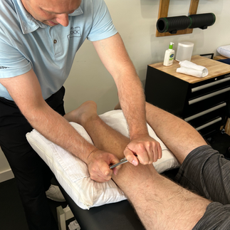 Integrative physical therapist Scraping a patient's leg using instrument assisted soft tissue massage to improve mobility and remove pain