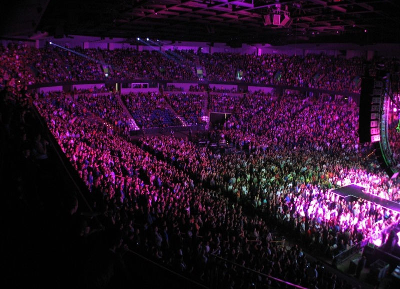 Packed concert arena, vibrant purple lighting