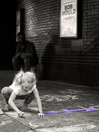 A child draws a chalk rainbow outside First Avenue, Minneapolis, April 23 2016, two days after Prince's death. Photograph by Timothy Harmon.