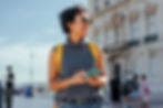 Young woman tourist with backpack using smart phone and exploring city during summer vacation