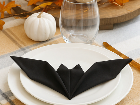 a table setting with a bat napkin on white plates