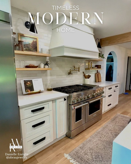 Modern kitchen with open shelves, white countertops and hood range with pot filler and stove