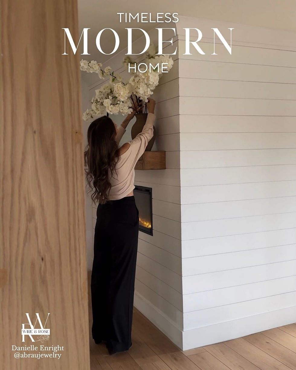 A woman decorating her mantel with white flowers in a vase