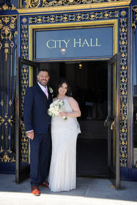 married couple stands in doorway of san francisco city hall