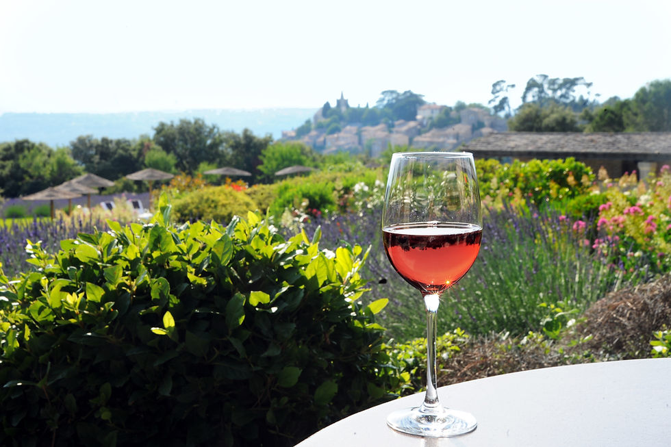 View of Bonnieux with glass of rosé in foreground, and lavender on the hills, trips to France planned by Viewfinder Travel for  luxury experiences, cultural interests, boutique hotels, art and wine 