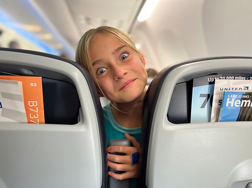 Young girl peeking between airplane seats during a family flight
