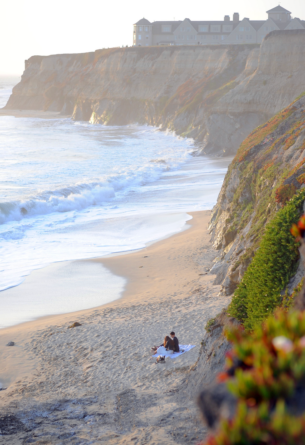 Couple sitting at a quiet beach picnic below the California coast