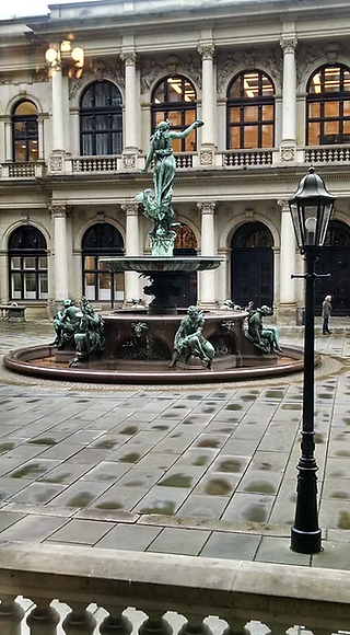 Fountain and courtyard near Hamburg’s historic buildings, wet cobblestones after rain