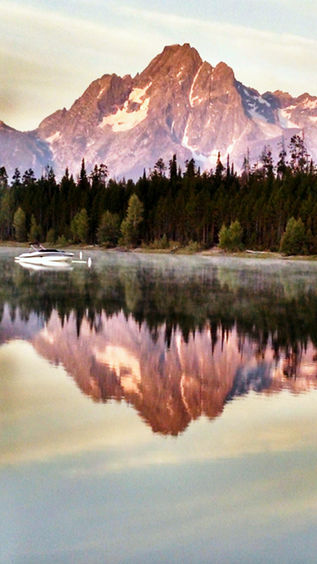 sunrise on the teton mountains in jackson hole overlooking june lake and a forest by holman photography