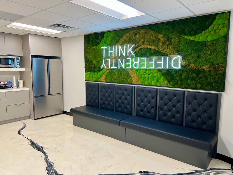 Interior design feature wall with moss textures and white LED lettering reading “THINK DIFFERENTLY,” above elegant navy bench seating.