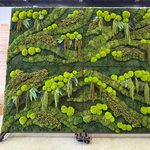 A large portable folding preserved moss wall with rich 3D green cushion moss and ferns mounted on a wheeled frame inside a warehouse setting.