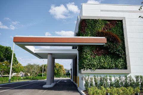 Exterior view of Valley Bank in Boca Raton with a large vertical green wall featuring layered tropical plants integrated into the building façade.