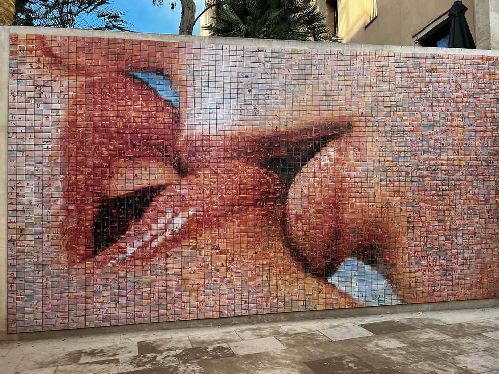 Mosaic of close-up lips on a wall, comprised of tiny colorful photos. Located outdoors with trees in the background, evoking a vibrant mood.