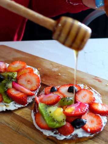 Colorful toast with fresh fruits and honey being drizzled on 
