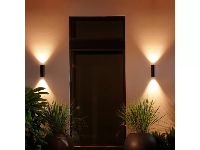 Philips Hue Appear Outdoor Wall Light mounted beside front door, illuminating entryway of modern rental property.