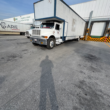 Camión de caja blanca para fletes y mudanzas estacionado en muelle.