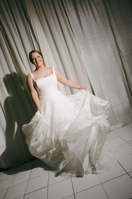 Woman in white dress spinning in front of a curtain