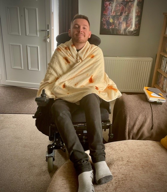 Ross sat in his wheelchair with his feet up on the sofa, wrapping his body in a tortilla blanket
