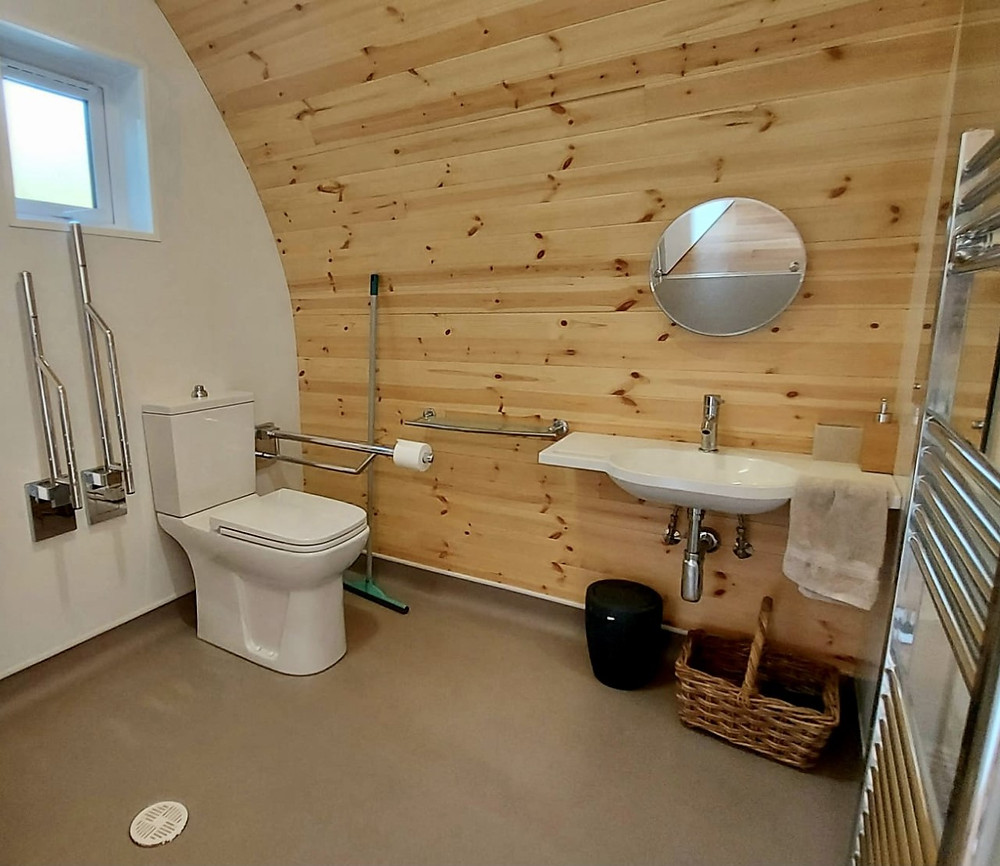 Wet-room bathroom inside the pod, showing grab rails around the toilet and a wheel-under sink