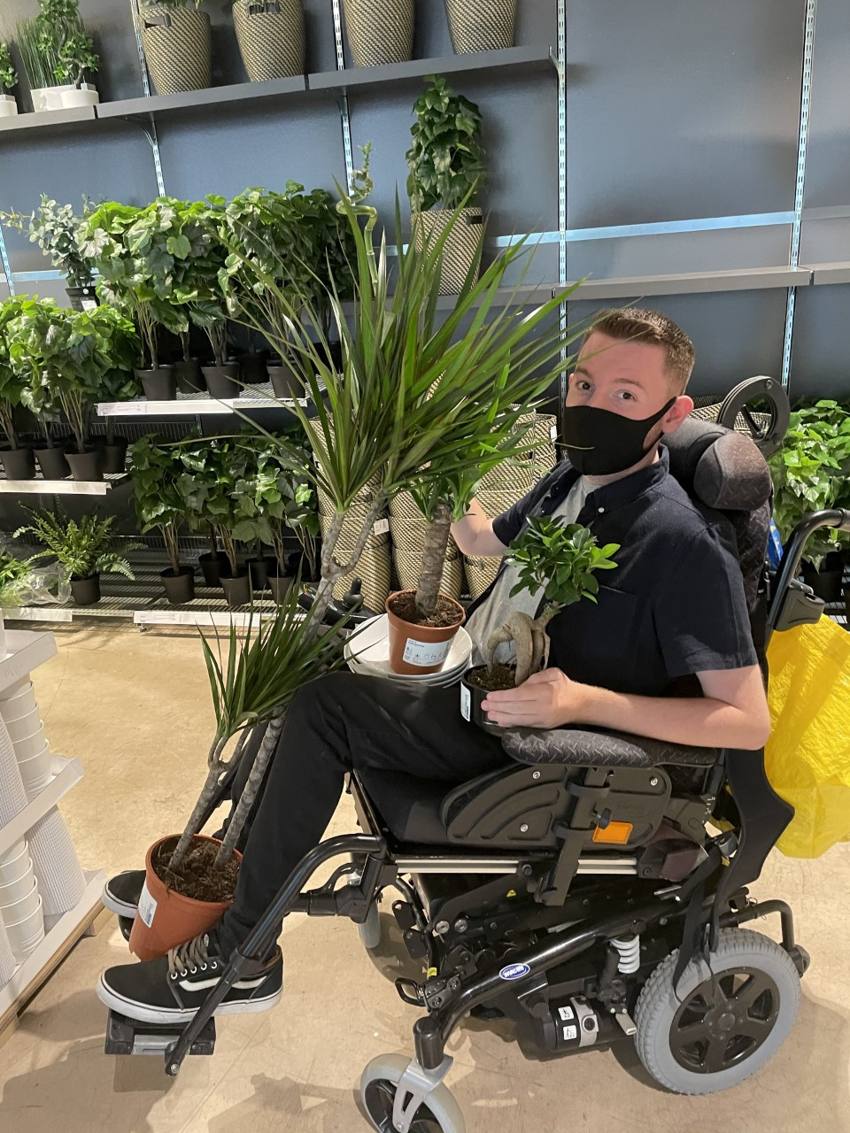 Ross inside IKEA with his wheelchair piled high with plants