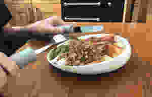Close up of the scoop dish with Ross's holding his cutlery, about to eat a roast dinner