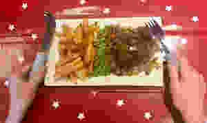 A shot of Ross's dinner (hamburger steak, chips and peas) holding a lightweight knife and fork