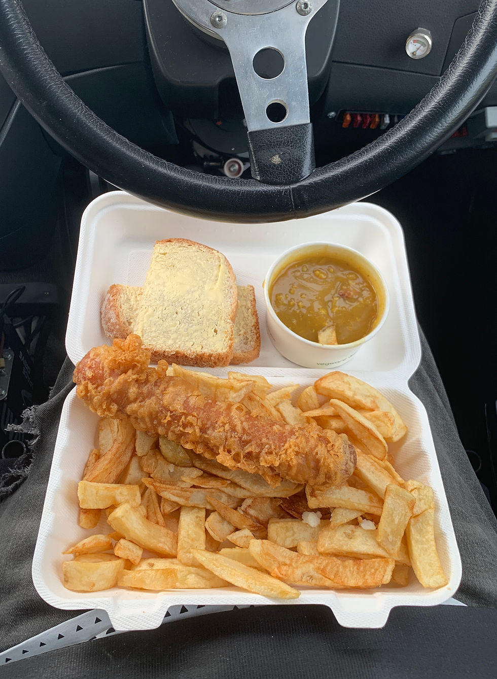 View of Ross's dinner on his lap - showing a jumbo battered sausage with chips, curry sauce and a bread butty