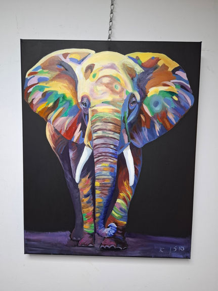 ציור צבעוני של פיל ענק, מציג ניבים לבנים, תלוי על קיר לבן.