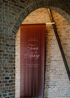 Elegant burgundy fabric welcome sign at an Iron Manor wedding with romantic luxury styling