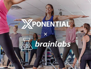 People in workout attire smiling while exercising in a gym. "XPONENTIAL" and "brainlabs" logos are overlaid. Bright, energetic mood.