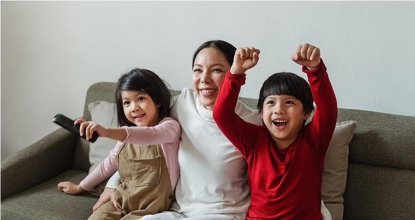 mom and two kids on the couch cheering