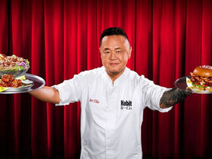 Chef Jet Tila in a white coat holds a burger and salad trays before red curtains, with Habit & Co. text.