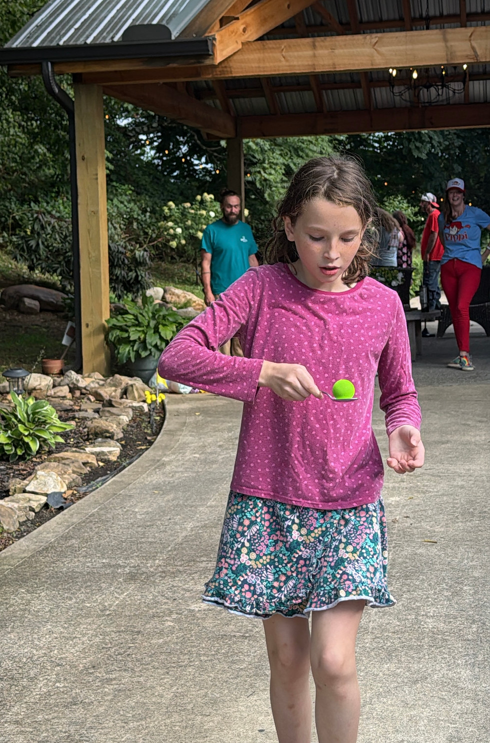 Child playing an outdoor spoon-and-ball game at a Solara community event