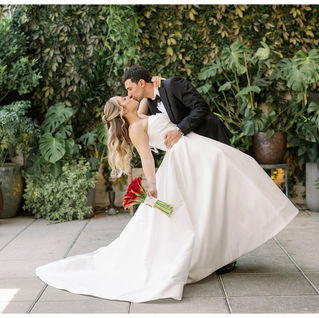 bride and groom dipping and kissing in front of live wall