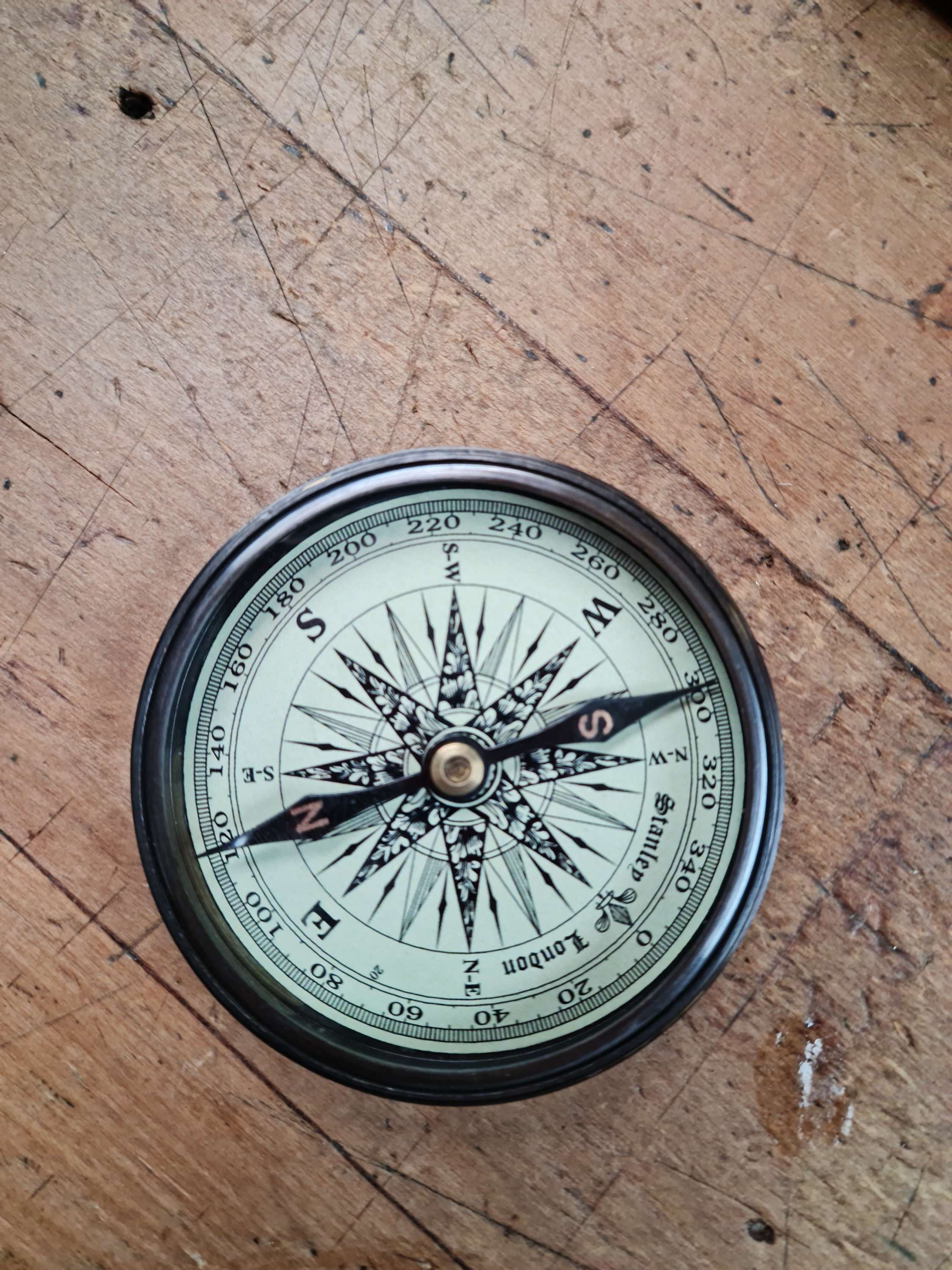 Antique compass on wooden surface showing direction and navigation details
