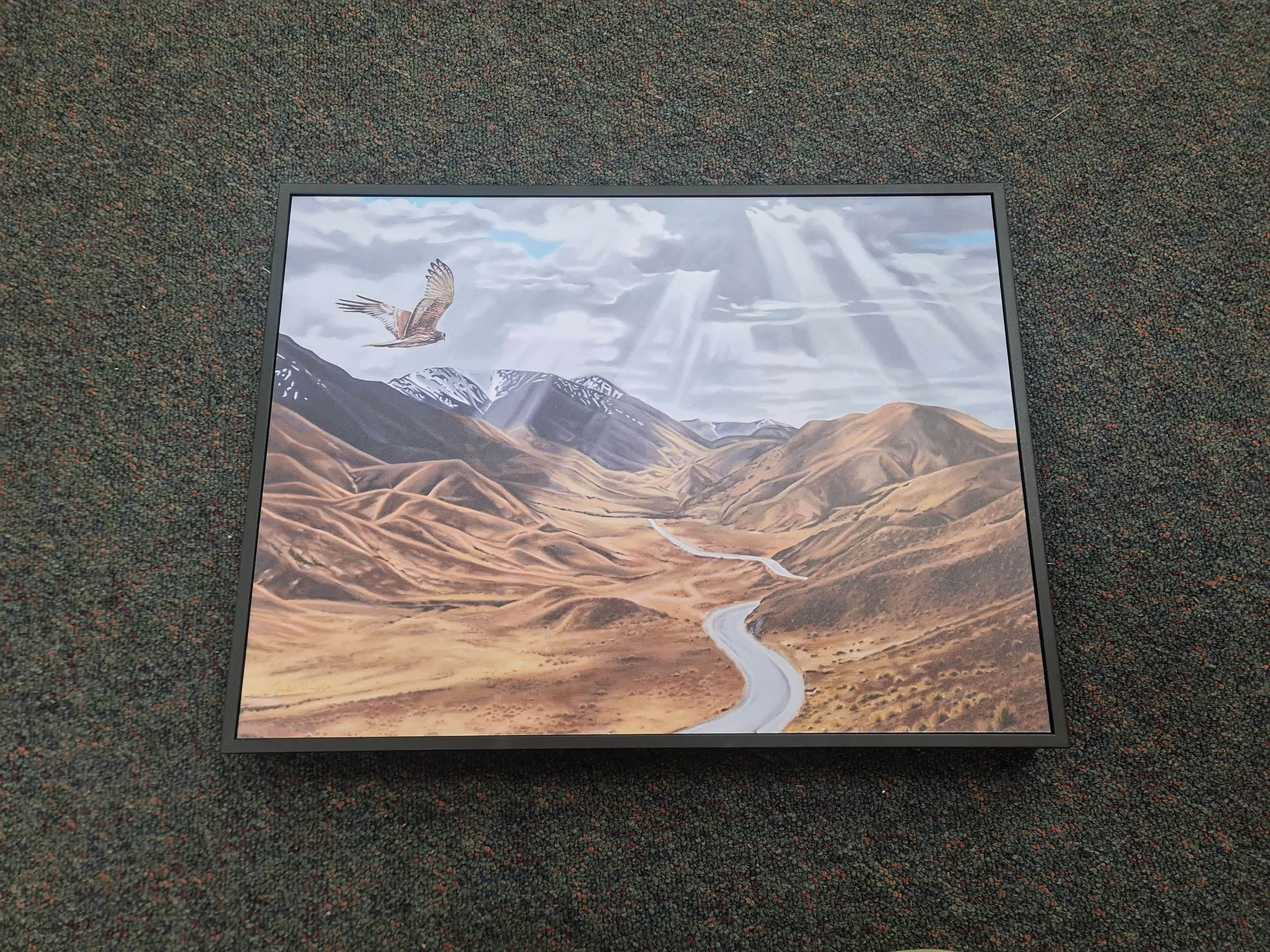 Framed landscape art with mountains and a road with an eagle in flight.