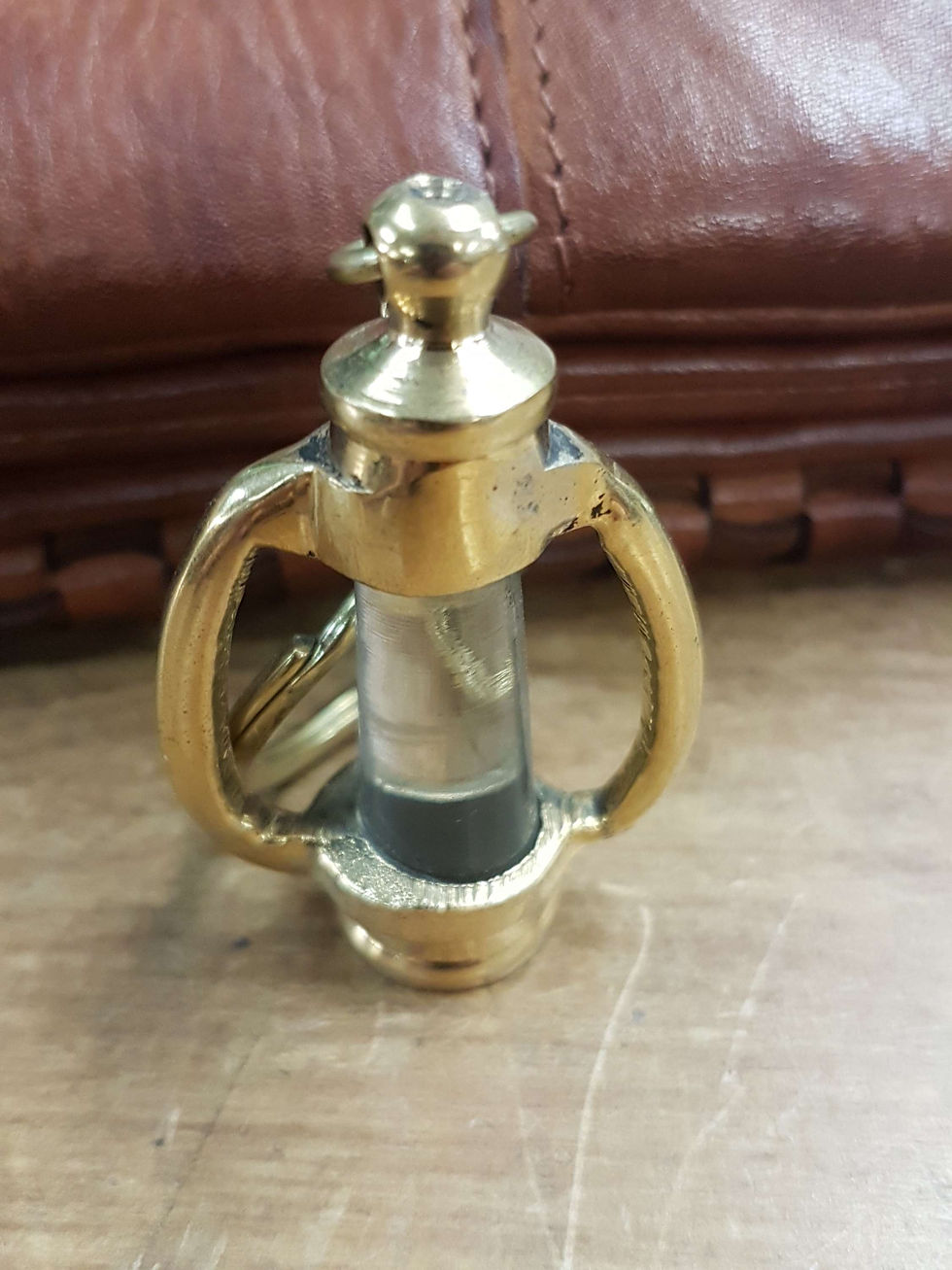 Thumbnail: Close-up of golden lantern keyholder. Background is a leather bag.