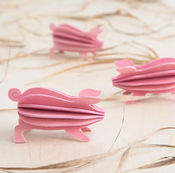 Thumbnail: Three pink wooden pigs, whimsical decor on a neutral background.