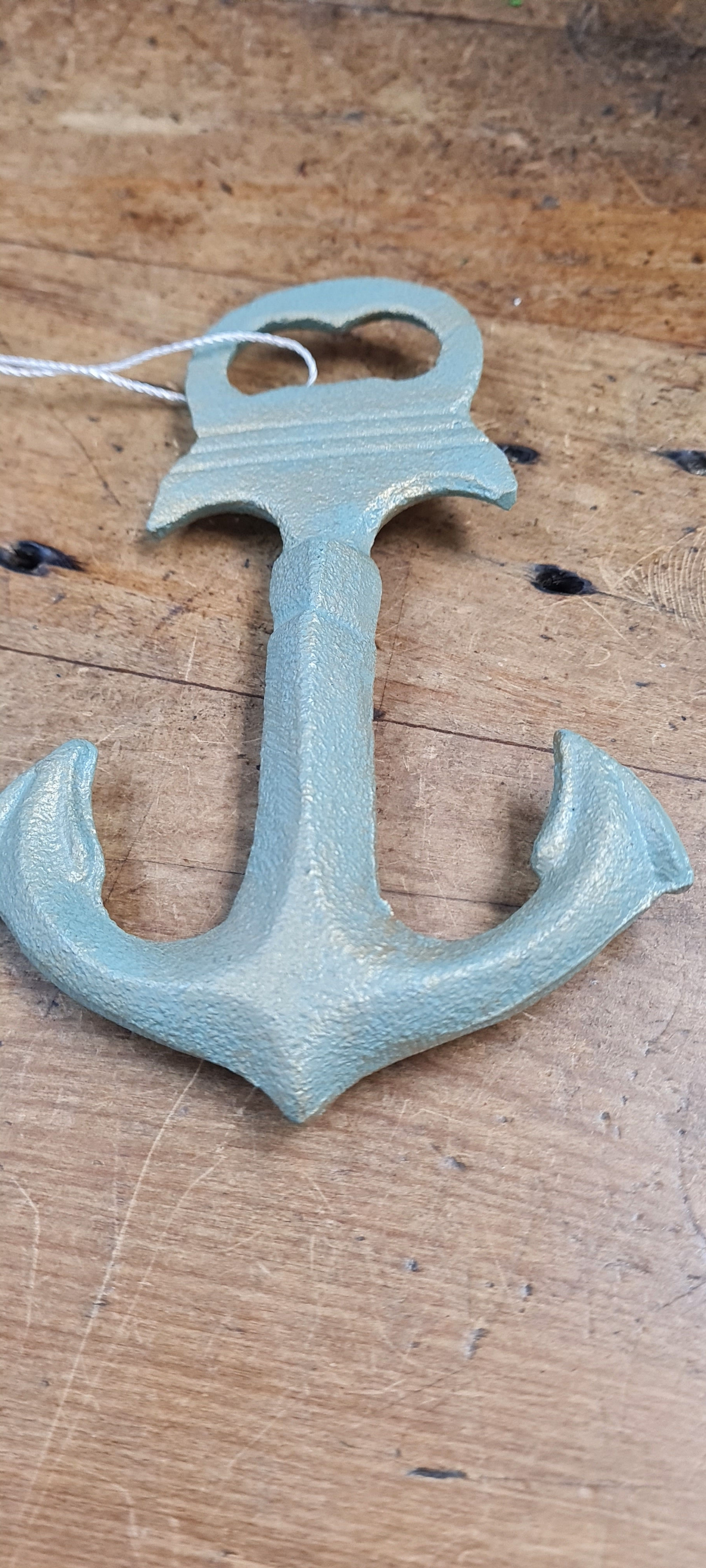 Light blue decorative anchor resting on a wooden surface, great home decor