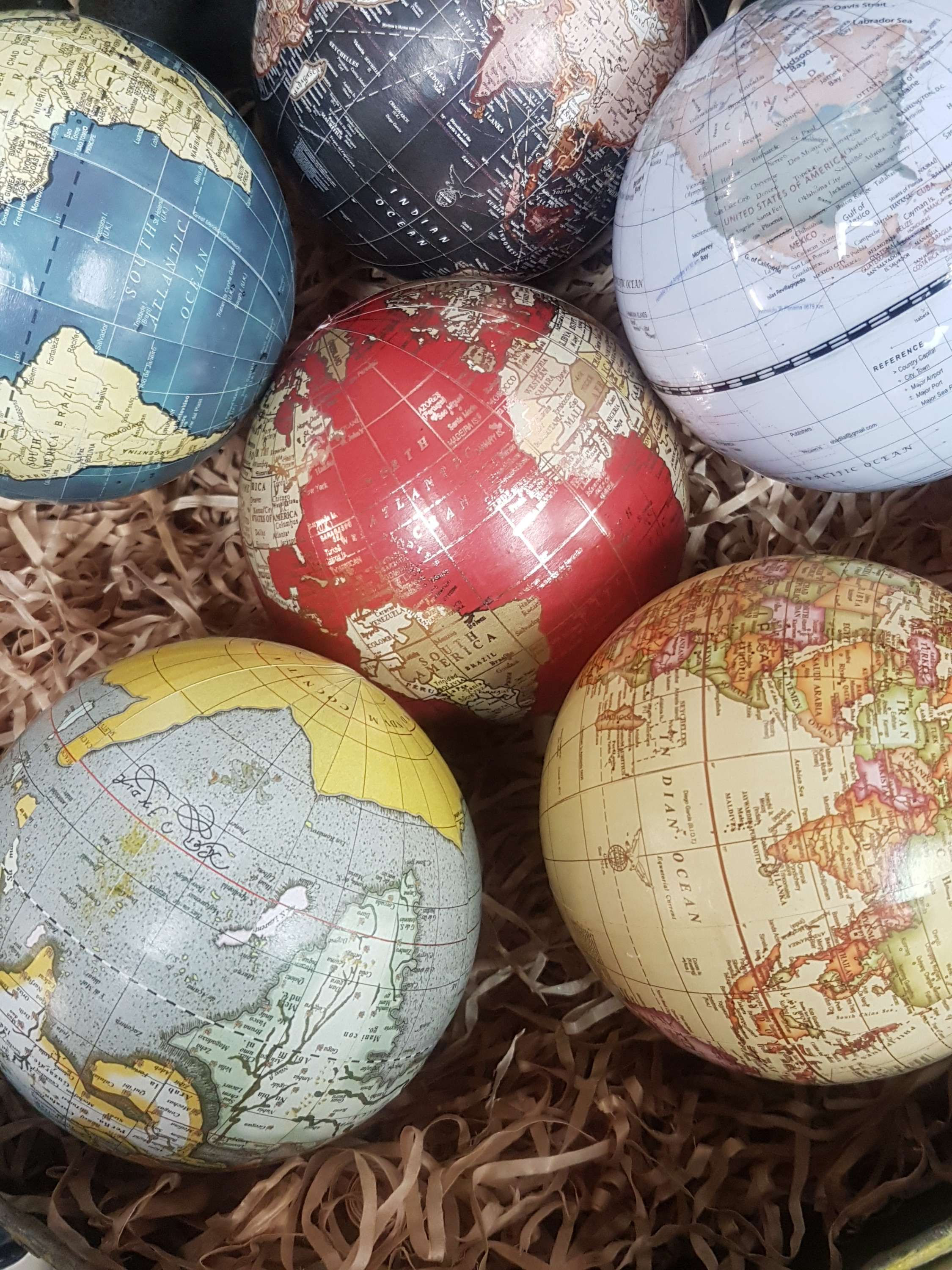 Close-up of several decorative globes with various colors and textures in a basket.