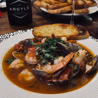 Plated cioppino with basil garnish and toasted bread